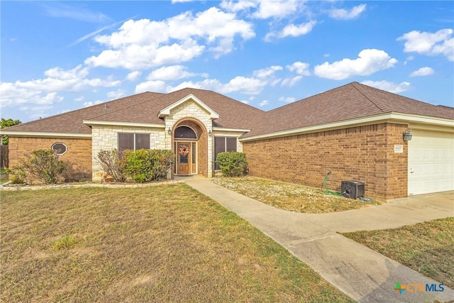 single story home featuring an attached garage, brick siding, stone siding, roof with shingles, and a front lawn