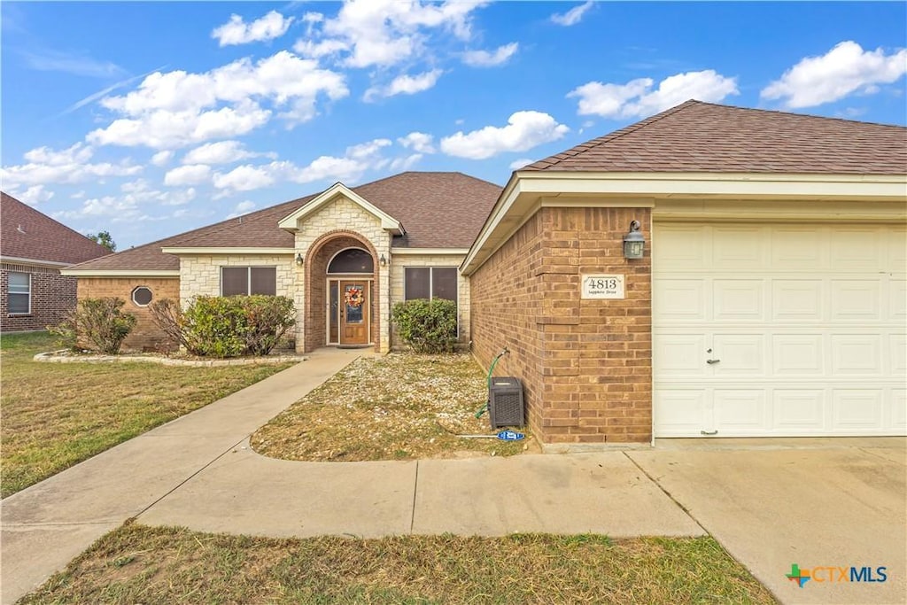 ranch-style home featuring a garage and a front lawn