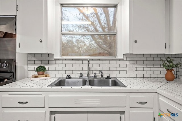 kitchen featuring white cabinets, sink, and backsplash