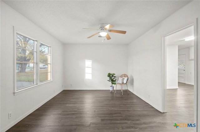 empty room with ceiling fan, dark wood-type flooring, and a textured ceiling