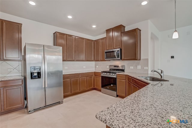 kitchen featuring stainless steel appliances, sink, kitchen peninsula, and decorative light fixtures