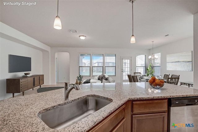 kitchen with sink, decorative light fixtures, dishwasher, a notable chandelier, and light stone countertops