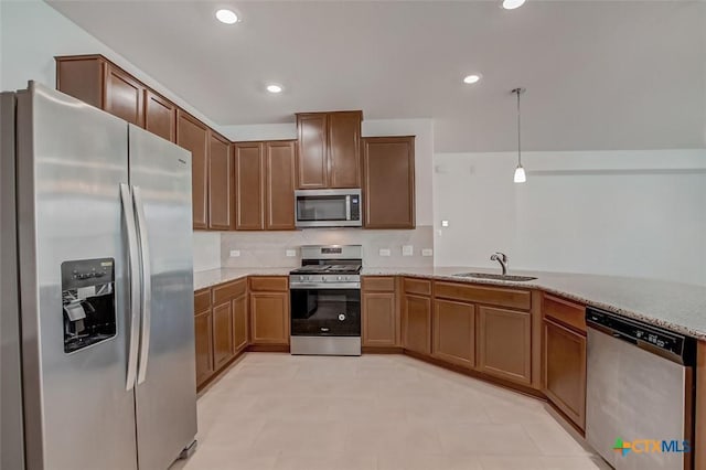 kitchen featuring sink, hanging light fixtures, appliances with stainless steel finishes, kitchen peninsula, and light stone countertops