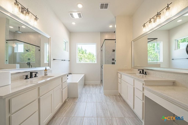 full bath featuring a stall shower, a bath, two vanities, recessed lighting, and marble look tile flooring