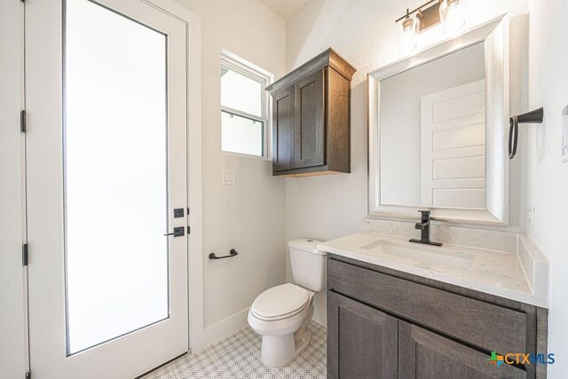 half bath with toilet, vanity, and baseboards