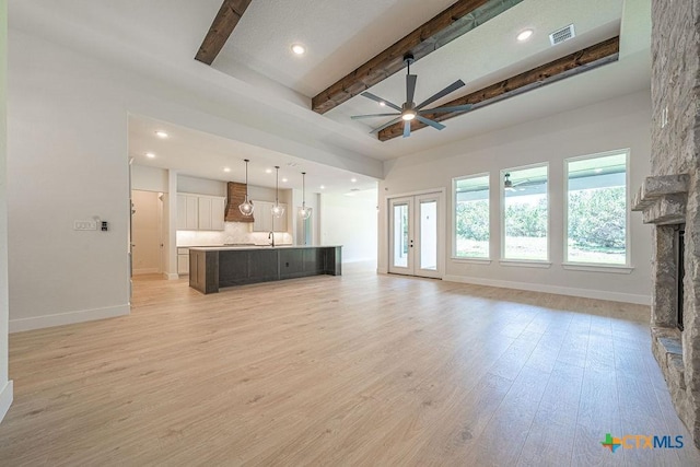 unfurnished living room with ceiling fan, beamed ceiling, baseboards, light wood finished floors, and recessed lighting