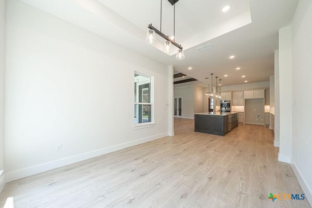 kitchen with a raised ceiling, light wood-style flooring, open floor plan, baseboards, and recessed lighting