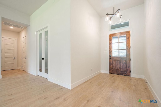 entrance foyer featuring wood finished floors, a chandelier, baseboards, and french doors