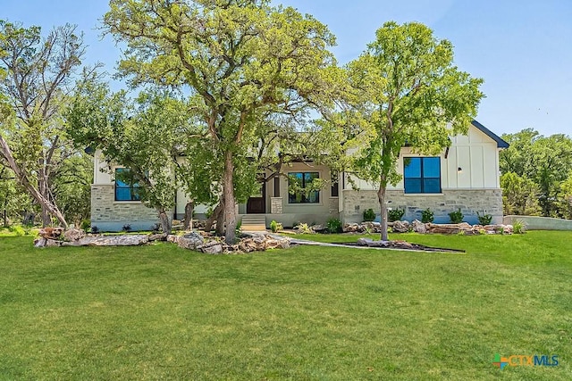 view of front of house featuring board and batten siding, stone siding, and a front lawn