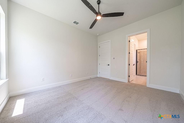 unfurnished bedroom featuring light colored carpet, baseboards, connected bathroom, and a ceiling fan