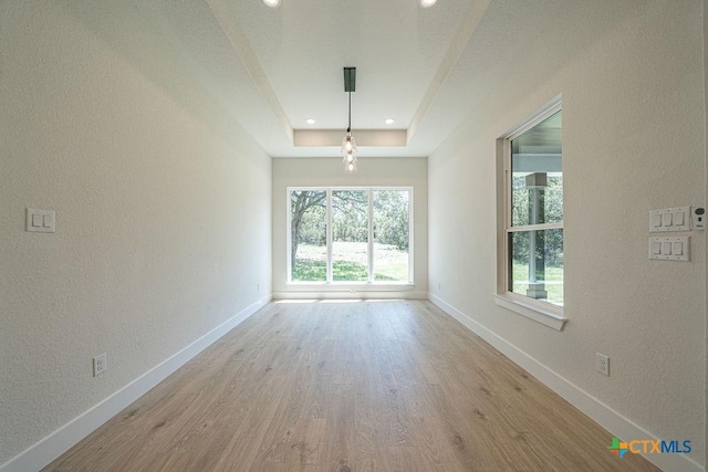 spare room featuring baseboards, wood finished floors, a textured wall, a raised ceiling, and recessed lighting