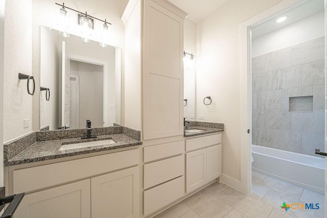 bathroom featuring double vanity, marble look tile flooring, baseboards, and bathing tub / shower combination
