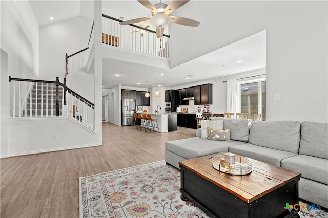 427 Bluejack Way, Hutto, TX 78634 - living area featuring light wood-style flooring, stairway, a towering ceiling, a ceiling fan, and recessed lighting