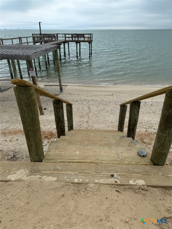 dock area featuring a water view and a beach view