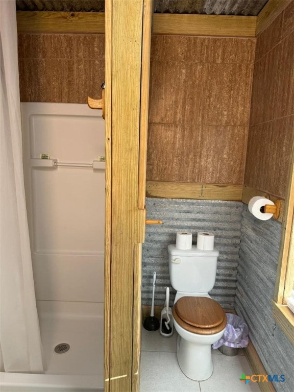 bathroom with a shower with curtain, tile patterned floors, and toilet