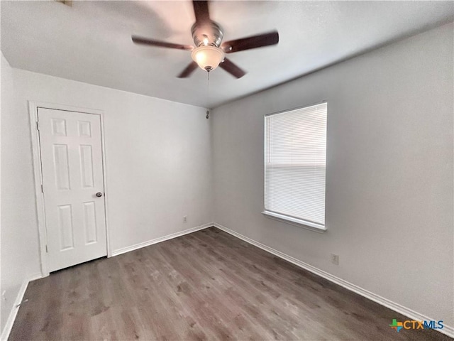 empty room featuring baseboards, wood finished floors, and a ceiling fan