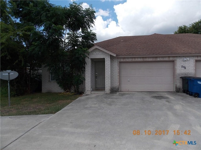 view of front of home with brick siding, concrete driveway, a shingled roof, and a garage