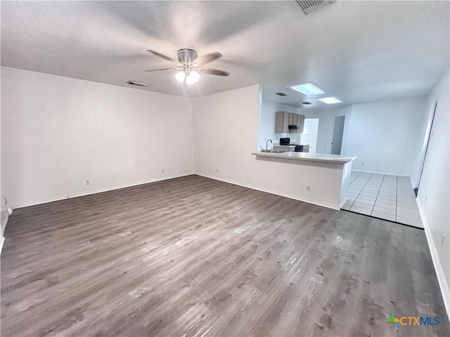 unfurnished living room with baseboards, wood finished floors, visible vents, and ceiling fan