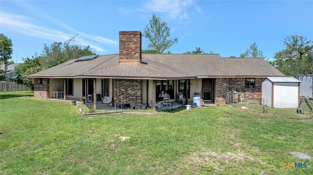rear view of house featuring a storage shed, a lawn, a patio area, brick siding, and a chimney