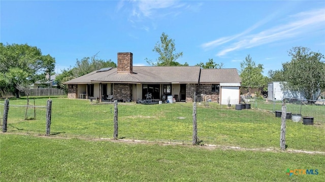 back of property with a yard, brick siding, fence, and a chimney