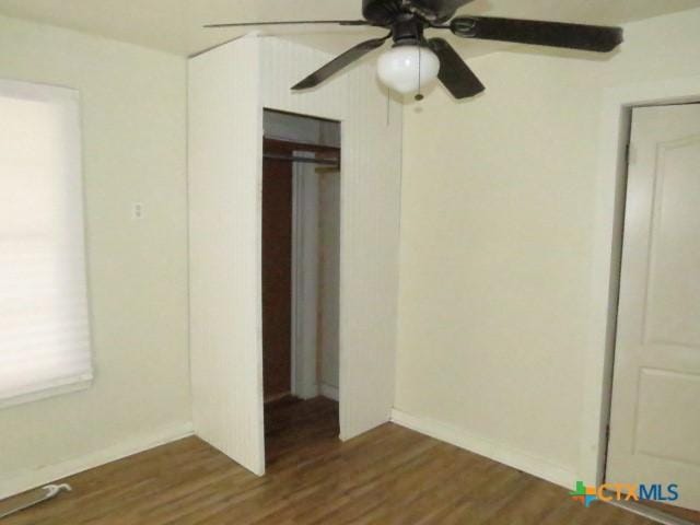 unfurnished bedroom with dark hardwood / wood-style flooring, a closet, and ceiling fan