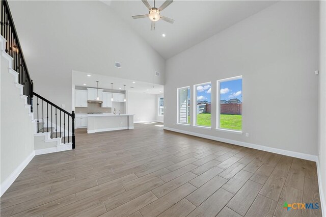 unfurnished living room with light hardwood / wood-style floors and a towering ceiling