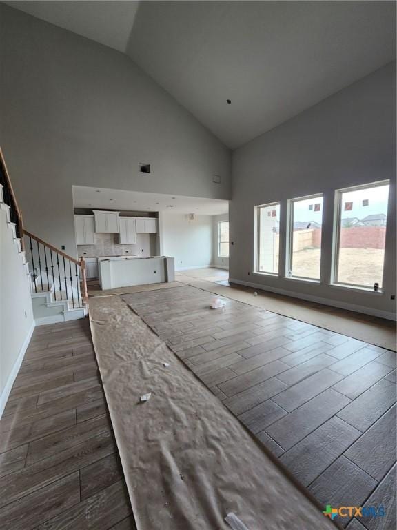 unfurnished living room featuring plenty of natural light and high vaulted ceiling