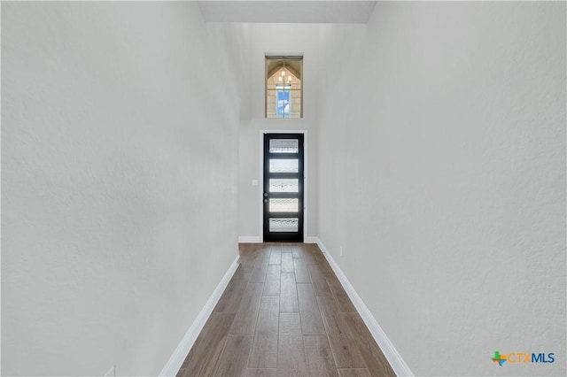 doorway with dark wood-type flooring and baseboards