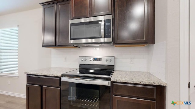 4013 Hayes Ct, Belton, TX 76513 - kitchen featuring appliances with stainless steel finishes, dark brown cabinetry, tasteful backsplash, light stone countertops, and baseboards