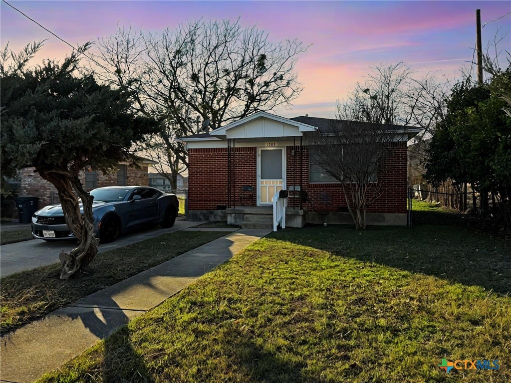 bungalow with brick siding, a front lawn, and fence