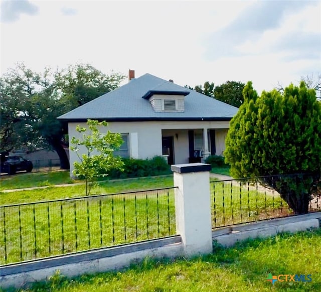 bungalow with a chimney, a fenced front yard, and a front yard