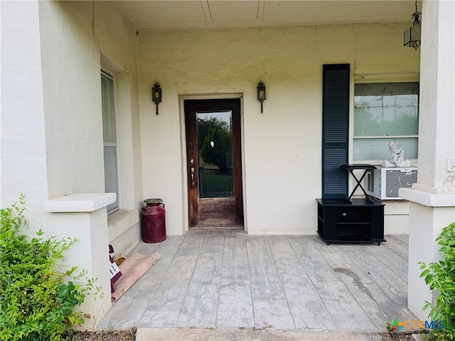 property entrance with stucco siding and cooling unit