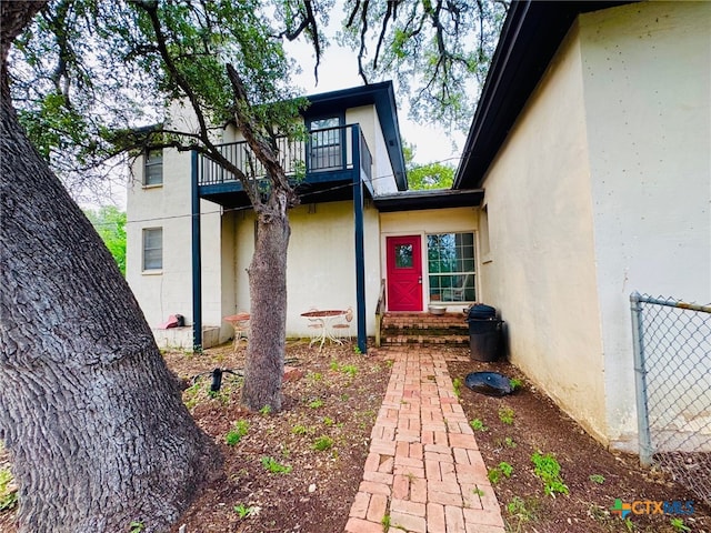 view of exterior entry with stucco siding and a balcony