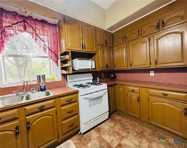kitchen featuring white appliances, tile countertops, a sink, and tasteful backsplash