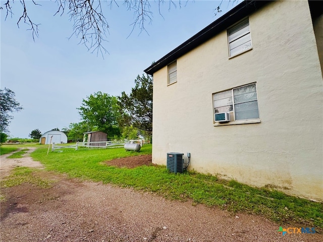 view of side of property featuring central air condition unit, a shed, an outdoor structure, and stucco siding