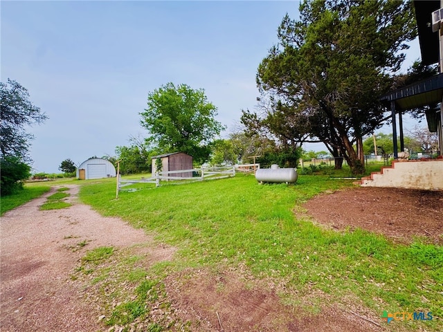 view of yard with a garage, an outdoor structure, and dirt driveway