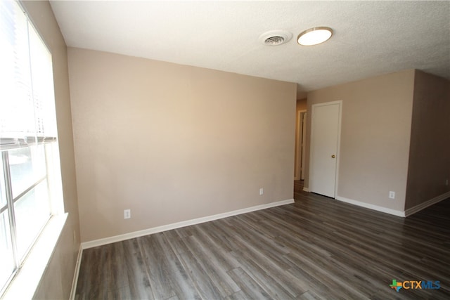 spare room featuring dark wood-type flooring and a textured ceiling