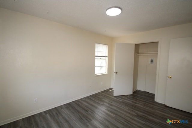 unfurnished bedroom featuring a closet and dark hardwood / wood-style floors