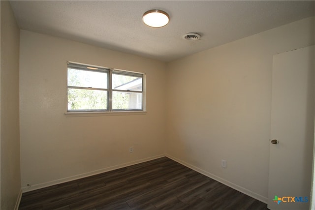 empty room featuring dark wood-type flooring and a textured ceiling