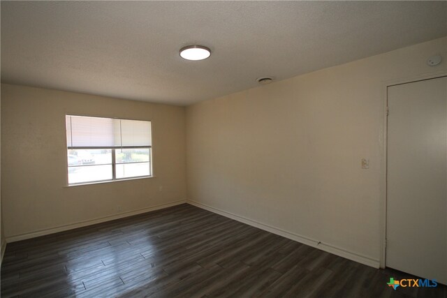 empty room with a textured ceiling and dark hardwood / wood-style floors