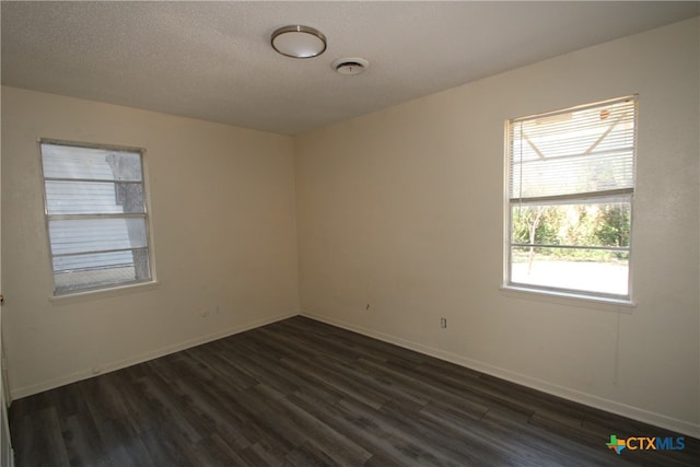 spare room featuring dark hardwood / wood-style flooring and a textured ceiling