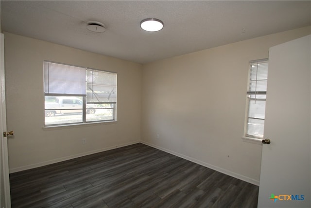 spare room featuring dark hardwood / wood-style floors and a textured ceiling