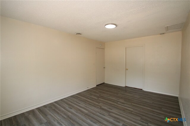 spare room with a textured ceiling and dark hardwood / wood-style floors