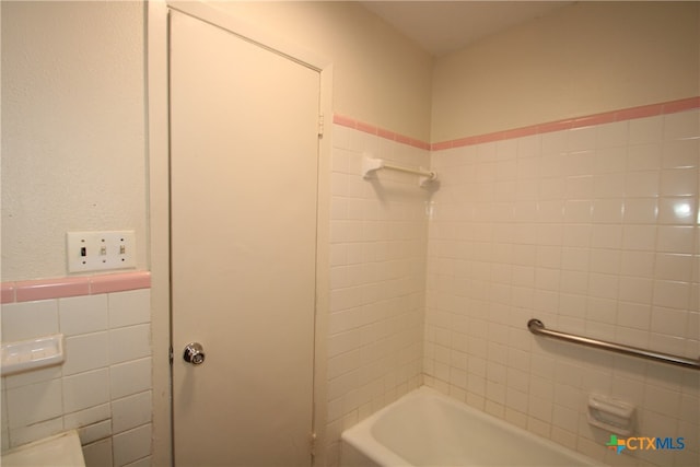 bathroom with tile walls and tiled shower / bath combo