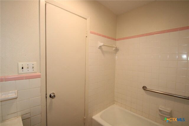 bathroom with tile walls and tiled shower / bath combo