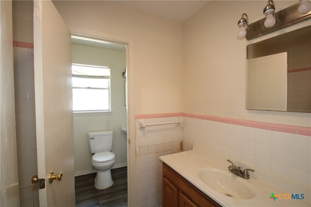 bathroom with hardwood / wood-style floors, vanity, toilet, and tile walls