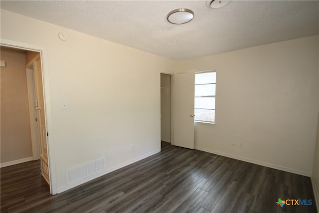 unfurnished room featuring a textured ceiling and dark hardwood / wood-style flooring