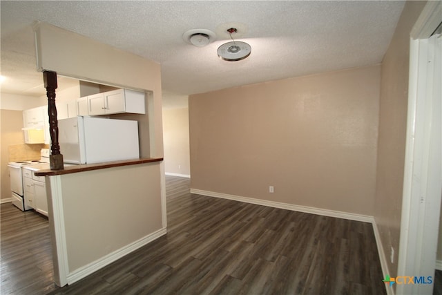 spare room with a textured ceiling and dark hardwood / wood-style floors