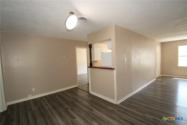 unfurnished room with a textured ceiling and dark hardwood / wood-style floors