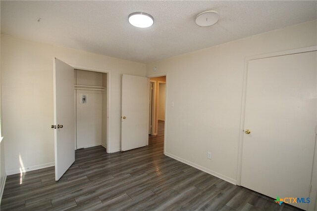 unfurnished bedroom with dark hardwood / wood-style flooring, a closet, and a textured ceiling